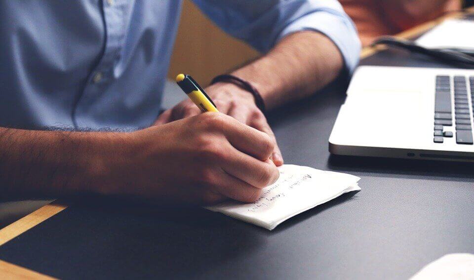 arms in front of computer writing notes preparing accounting and tax services ATS Accounting Edmonton